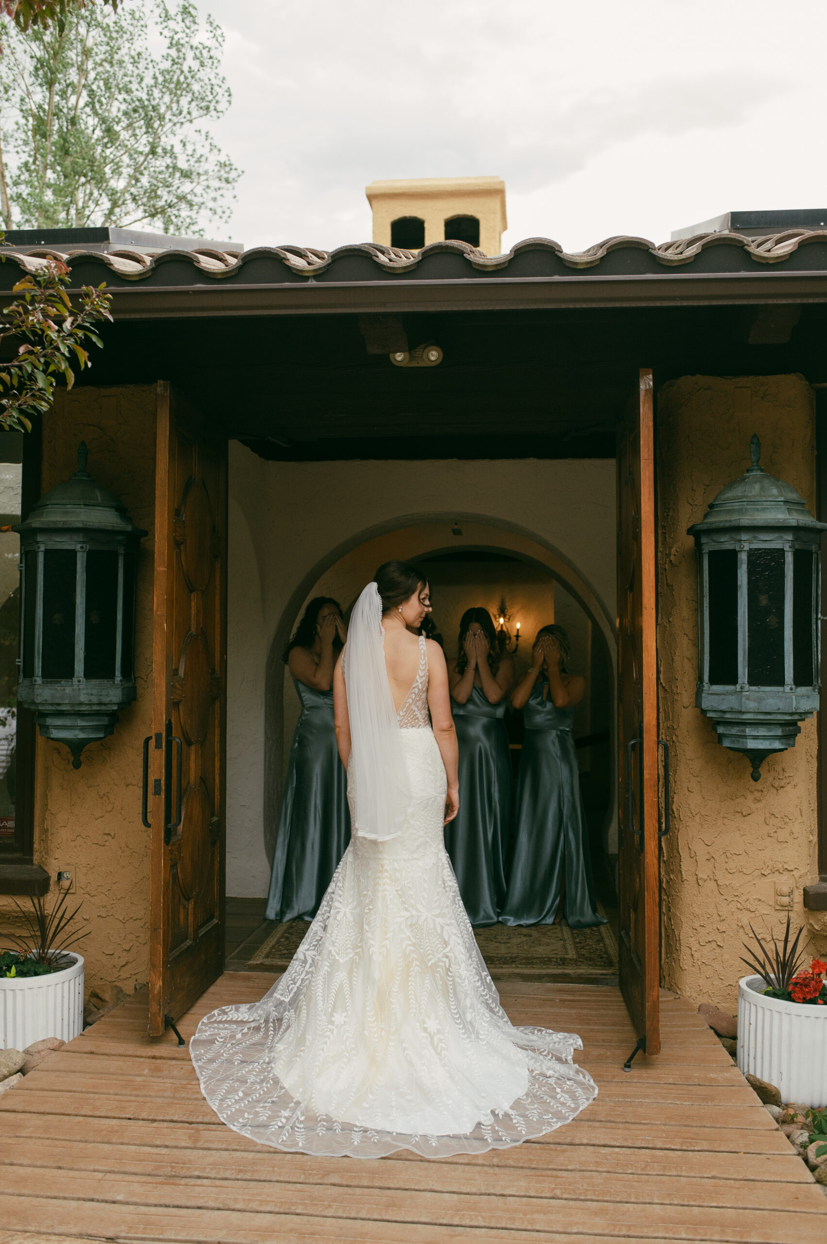 The first look between a bride and her bridesmaids in the front intricate doors of Villa Parker in Colorado.