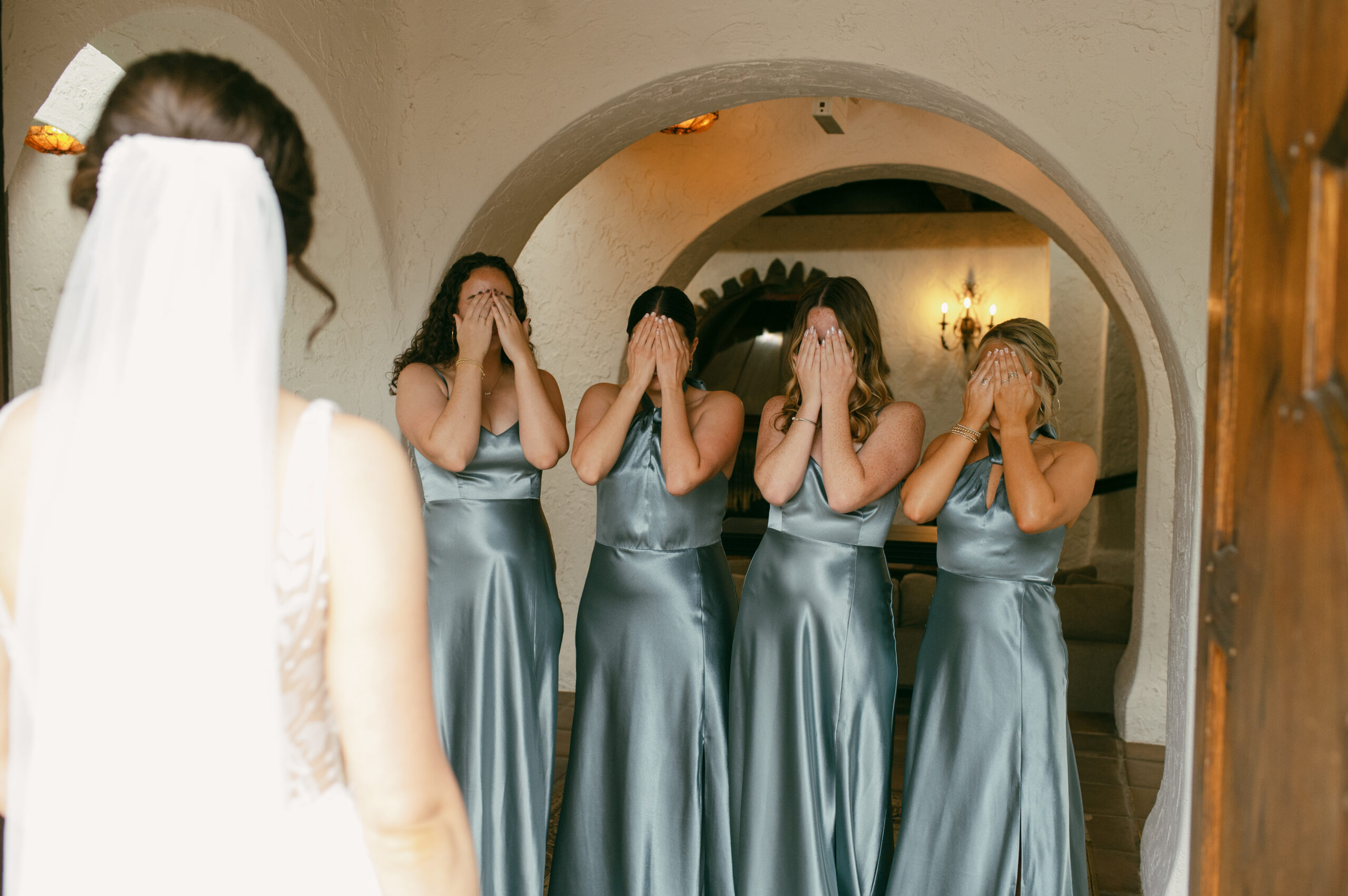 The first look between a bride and her bridesmaids in the front intricate doors of Villa Parker in Colorado.