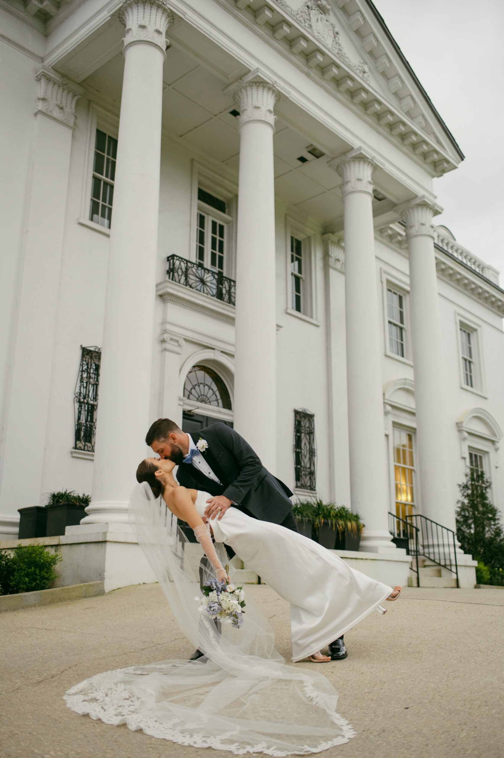 A bride and groom dip-kissing in front of the old governor's mansion in louisiana.
