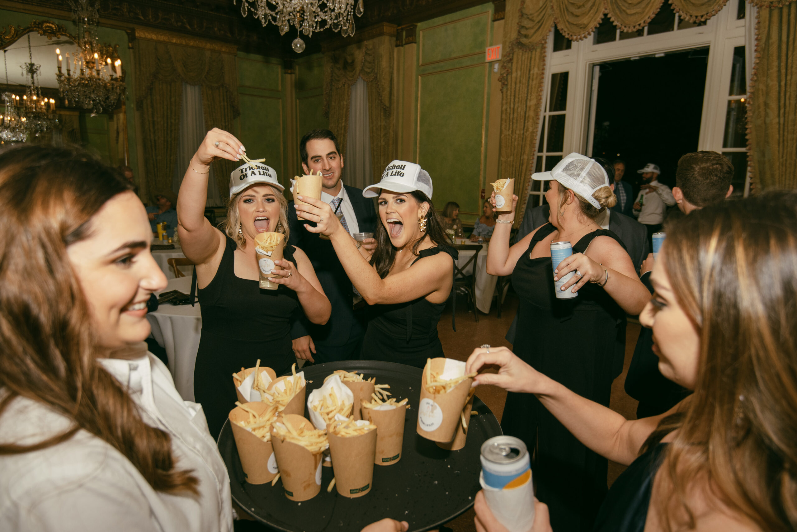 The bridesmaids are celebrating as parmesan truffle fries are passed around the reception as a late night snack.