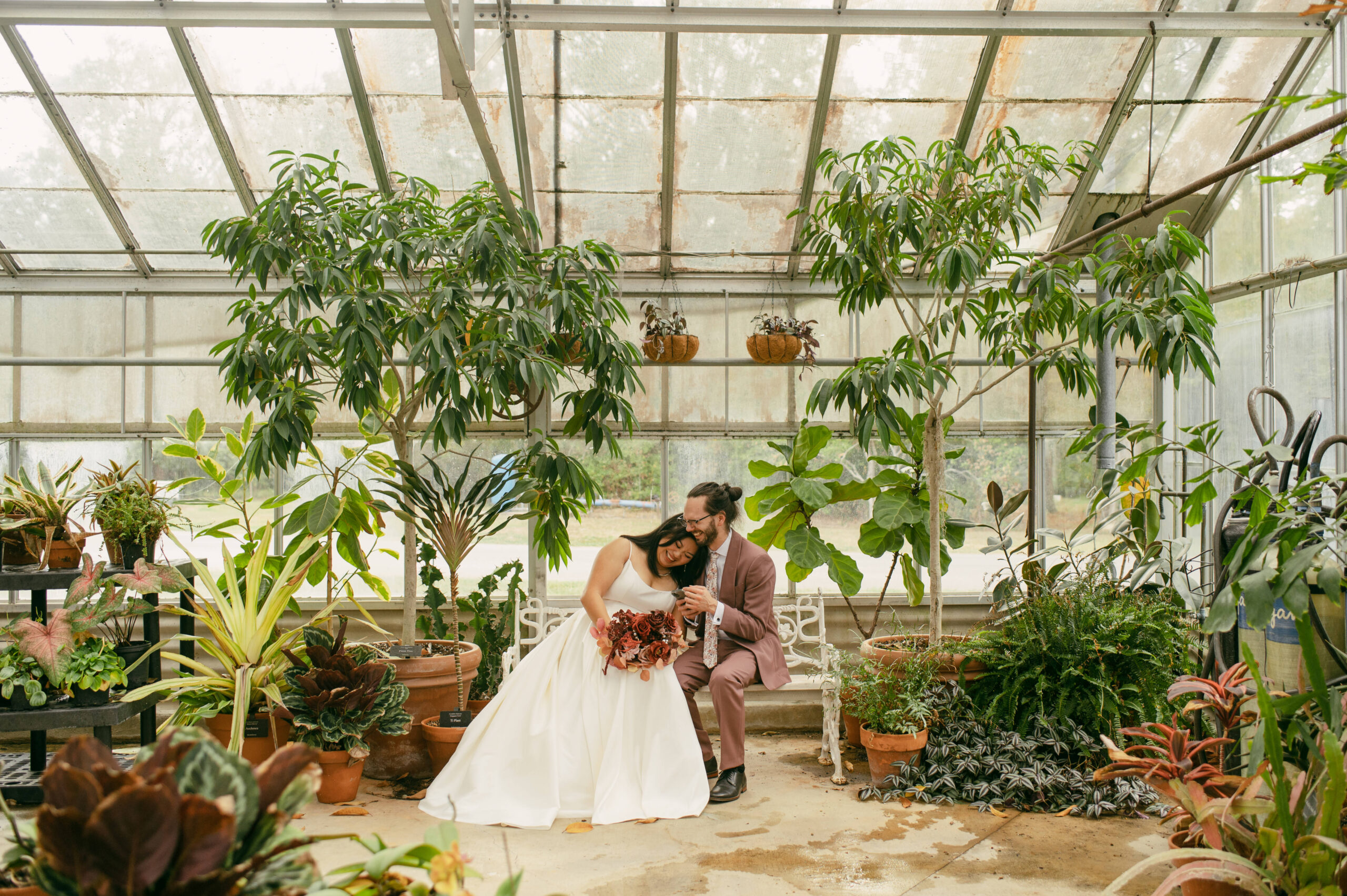 A couple reads private vows during their first look in a greenhouse.