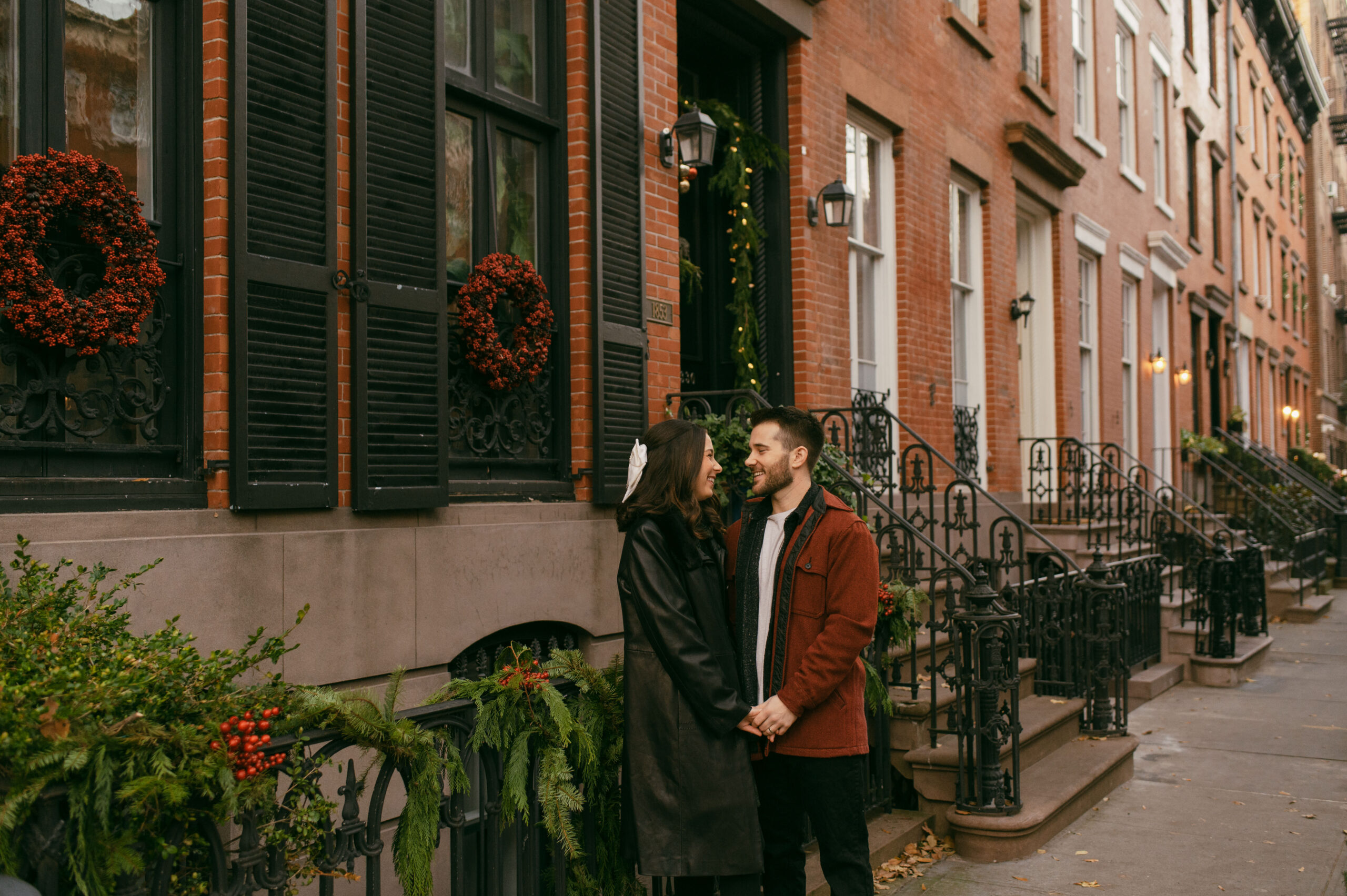A couple posed in front of a decorated brownstone