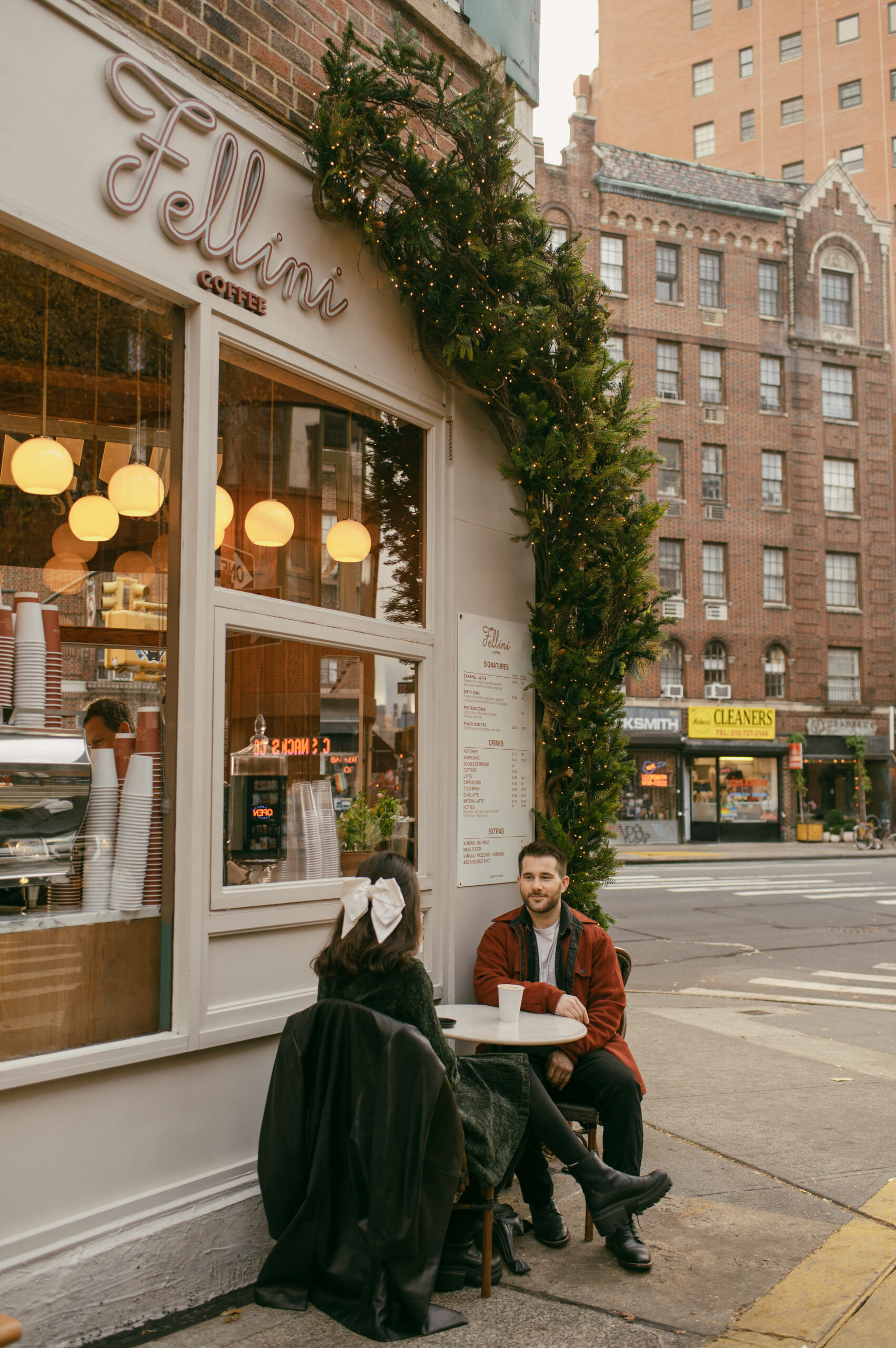 Fellini Coffee in West Village is a 16 square footage coffee shop on a triangular corner. A couple sits outside sipping coffee during their photoshoot.