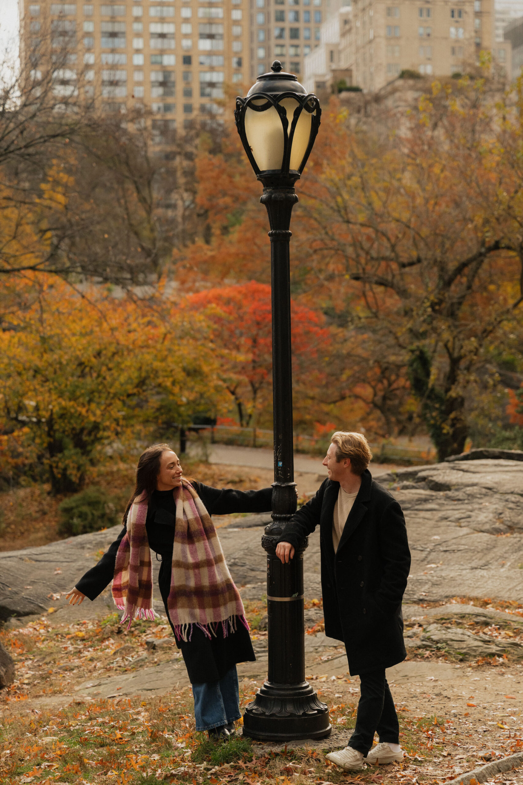 A couple swinging on a lamp post in Central Park during the Fall season surrounded by yellow and orange trees | | New york City Wedding Photographer
