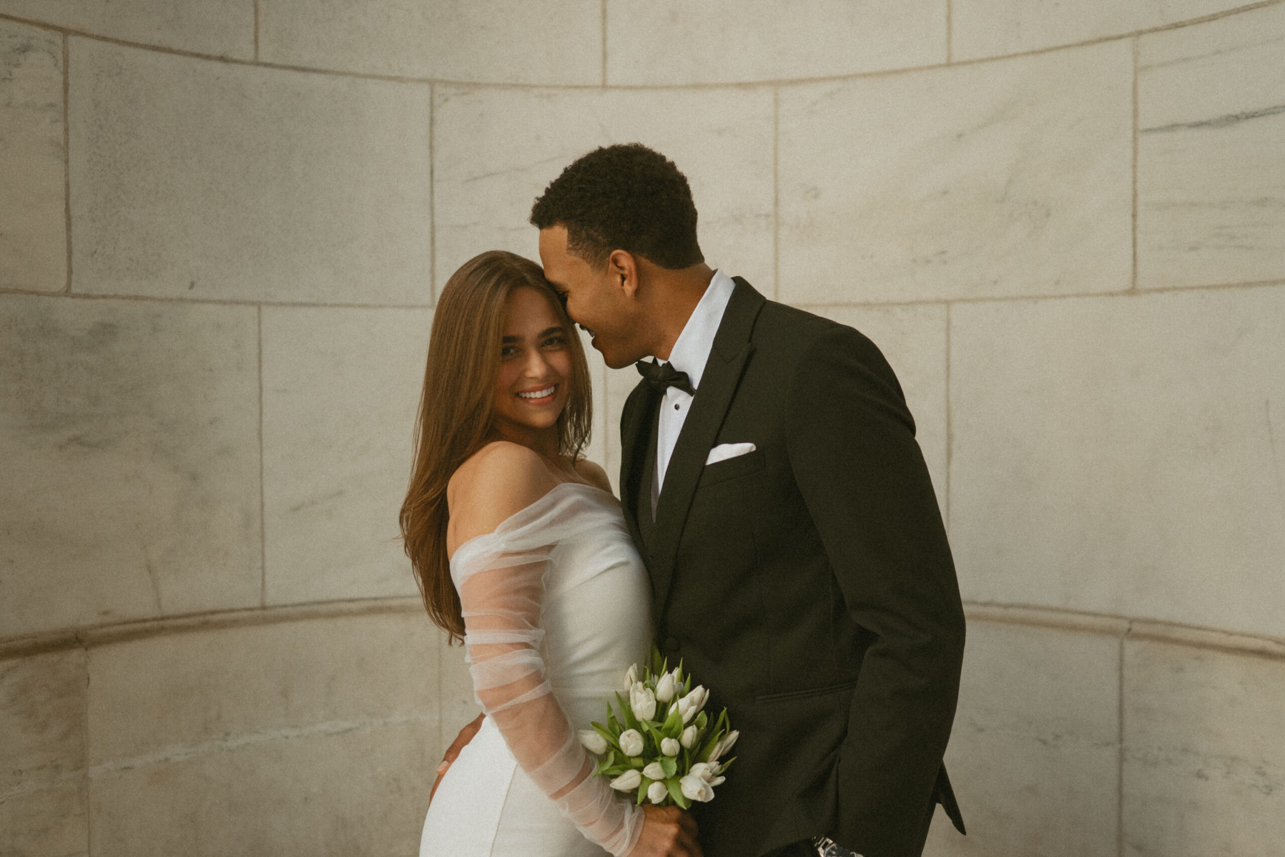 Newly married couple embracing outside NYC City Hall after their civil ceremony.